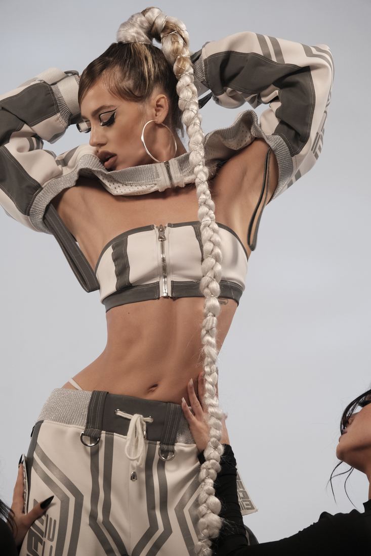 Sa Tiva in a white and grey moto-inspired set, arms raised